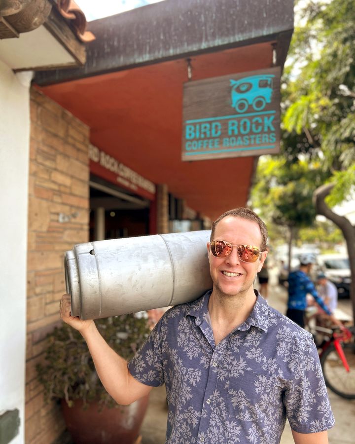 A Perpetual founder carrying a Bird Rock Coffee Roasters cold brew keg outside the Bird Rock Coffee Roasters cafe in La Jolla