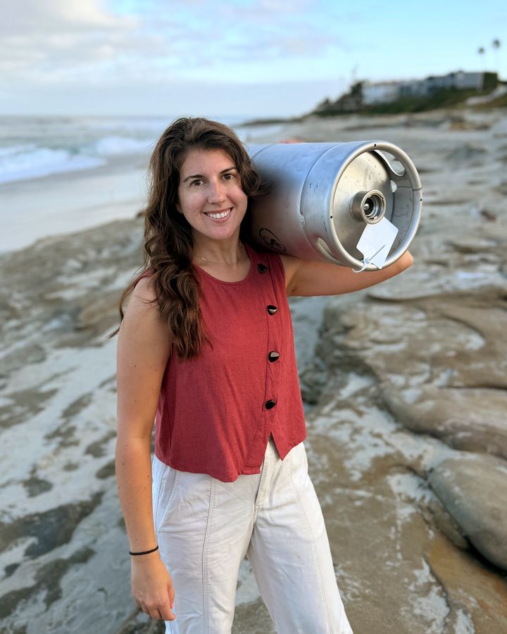 A Perpetual founder with an AleSmith beer keg on one shoulder on the rocks at Windansea Beach in La Jolla