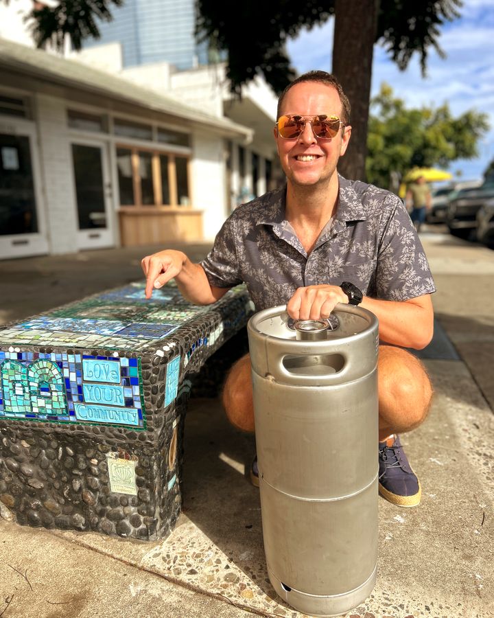 A Perpetual founder with a Bird Rock Coffee Roasters La Luna nitro cold brew keg beside the Love Your Community mosaic bench in Bird Rock, La Jolla