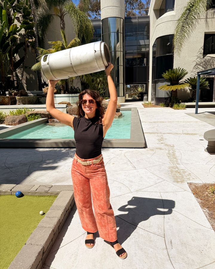 A Perpetual founder holding a Steady State Roasting cold brew keg overhead during an office delivery in Sorrento Valley