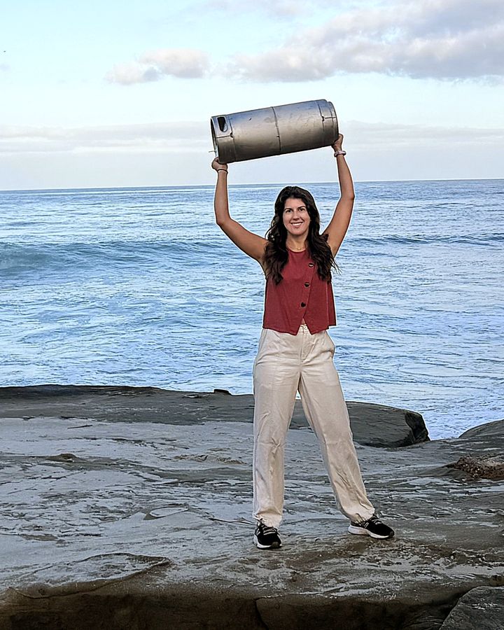 A Perpetual founder holding an AleSmith beer keg overhead on the rocks at Windansea Beach in La Jolla